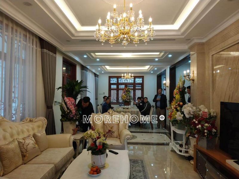Không gian phòng khách tân cổ điển được bày trí bộ sofa da, đèn chùm, kệ trang trí cao cấp,...